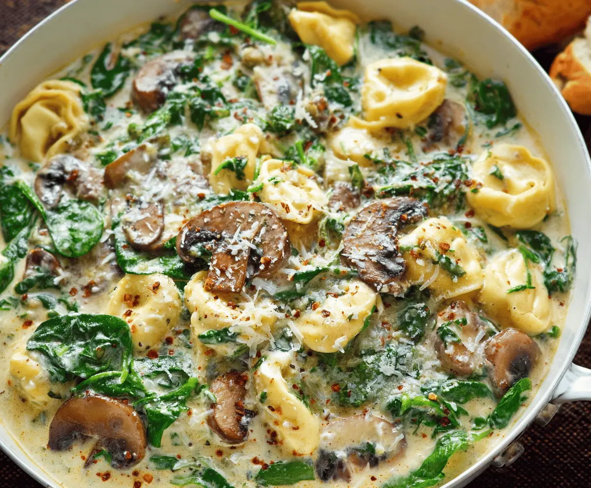 Creamy tortellini pasta with fresh spinach and sautéed mushrooms served in a bowl, delicious Italian-inspired dish