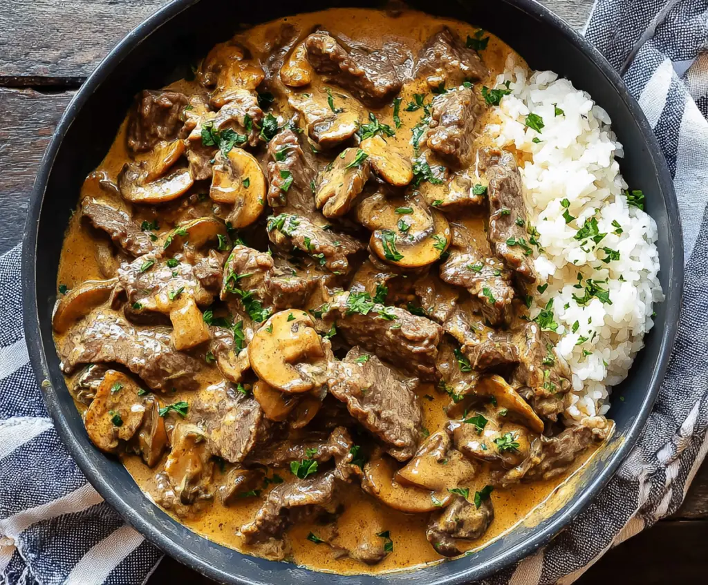Creamy beef stroganoff served over noodles with fresh herbs.