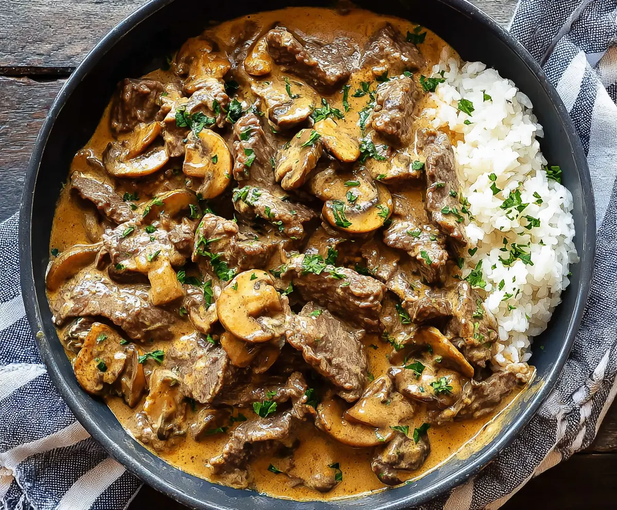 Creamy beef stroganoff served over noodles with fresh herbs.