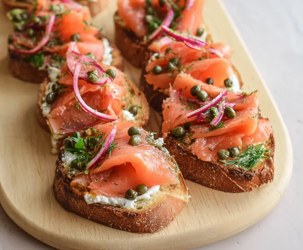 Delicious smoked salmon bruschetta topped with fresh herbs on a rustic wooden board