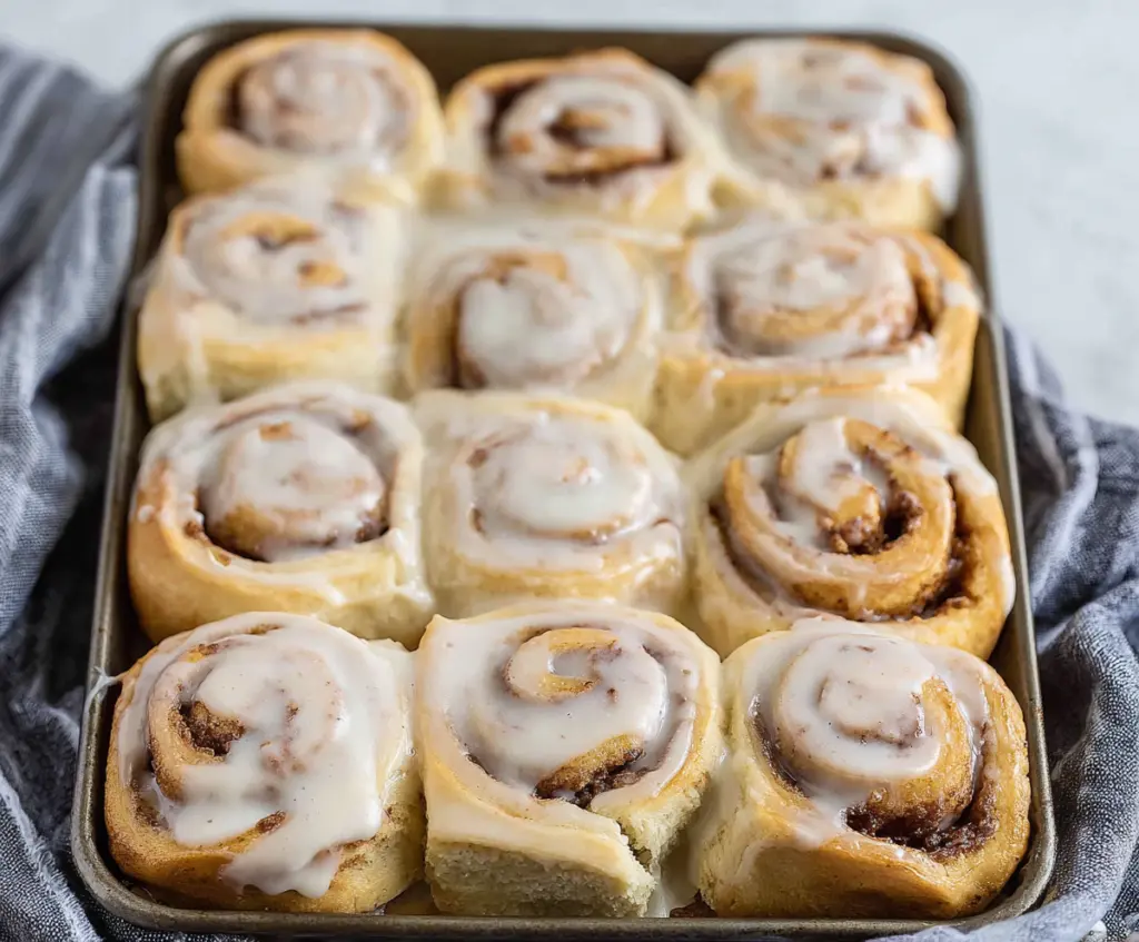 Delicious 30-minute sourdough discard cinnamon rolls topped with glaze on a rustic plate.